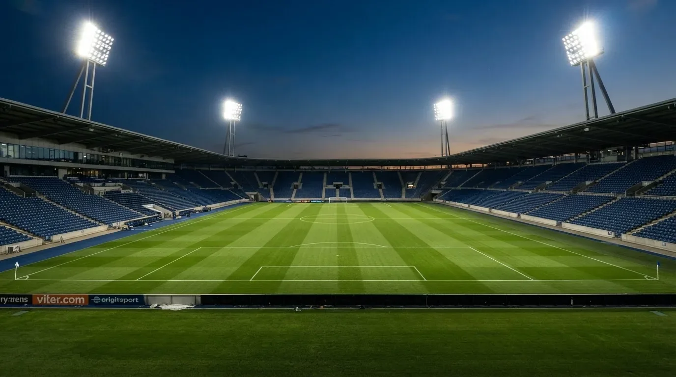 An empty football stadium with floodlight masts at dusk